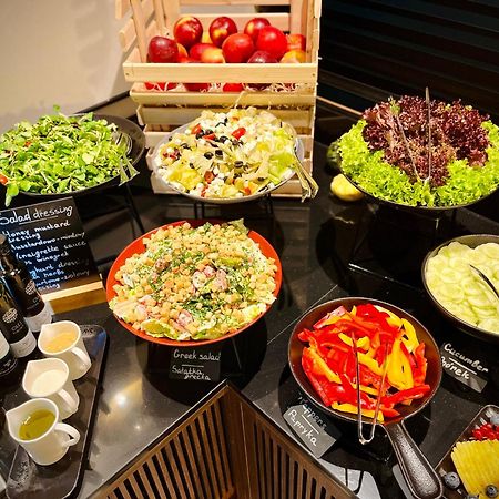 Royal Tulip Warsaw Centre Aparthotel Exterior foto The photo shows a well-arranged salad bar featuring a variety of fresh salads and ingredients. There are several bowls and dishes with different types of salads, including green salads and grain salads. 

1. **Green Salads**: There are multiple bowls