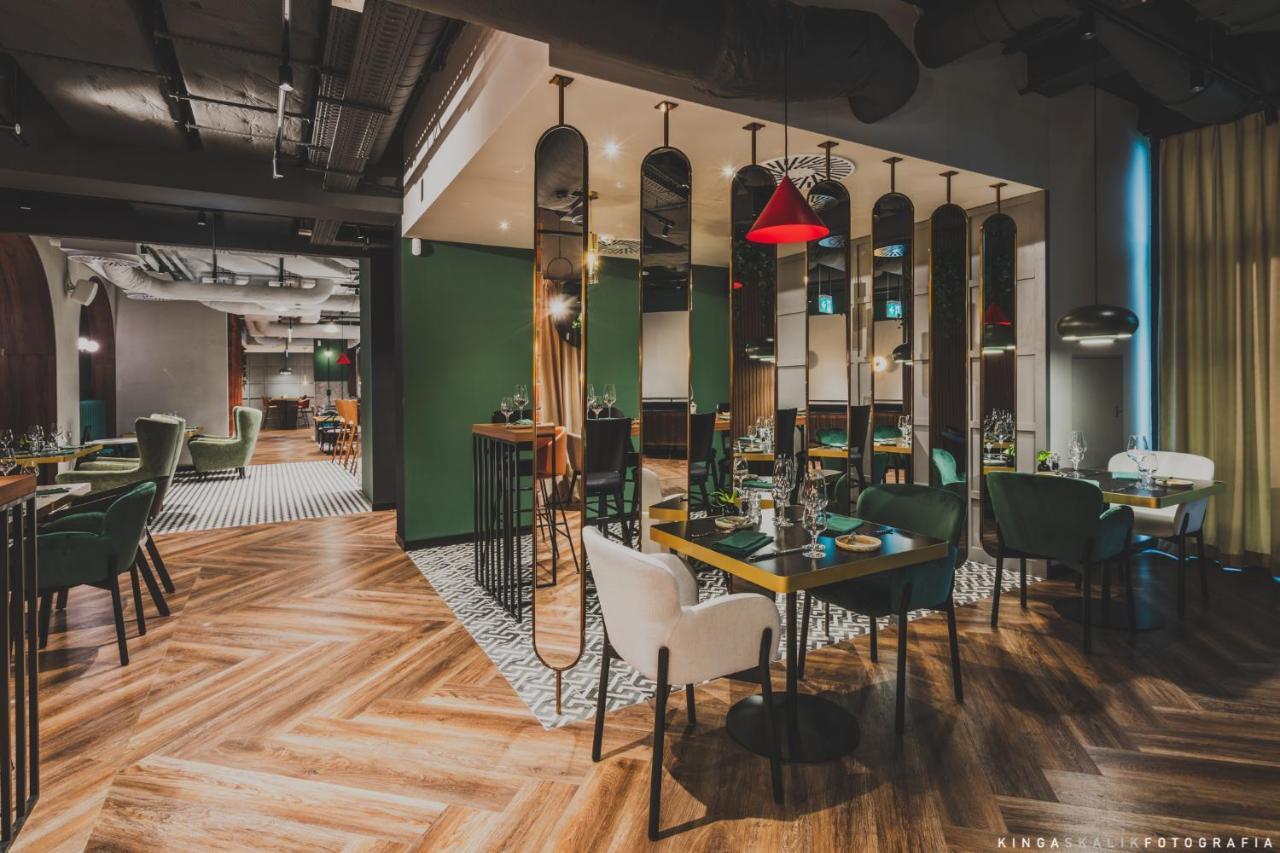 Royal Tulip Warsaw Centre Aparthotel Exterior foto The image depicts a modern restaurant interior. It features a combination of stylish furniture, including green and white chairs around wooden tables. The floor has a distinctive herringbone pattern, and there are mirrors along the walls, adding dept