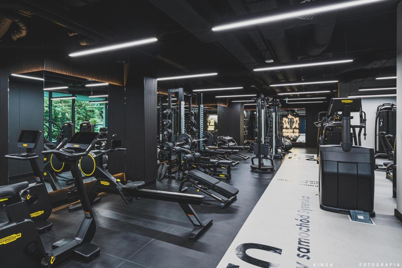 Royal Tulip Warsaw Centre Aparthotel Exterior foto The photo shows a modern gym interior with a sleek design. It features a variety of exercise equipment, including weight machines, free weights, and cardio machines. The space is well-lit with overhead lighting, and there are large windows allowing n