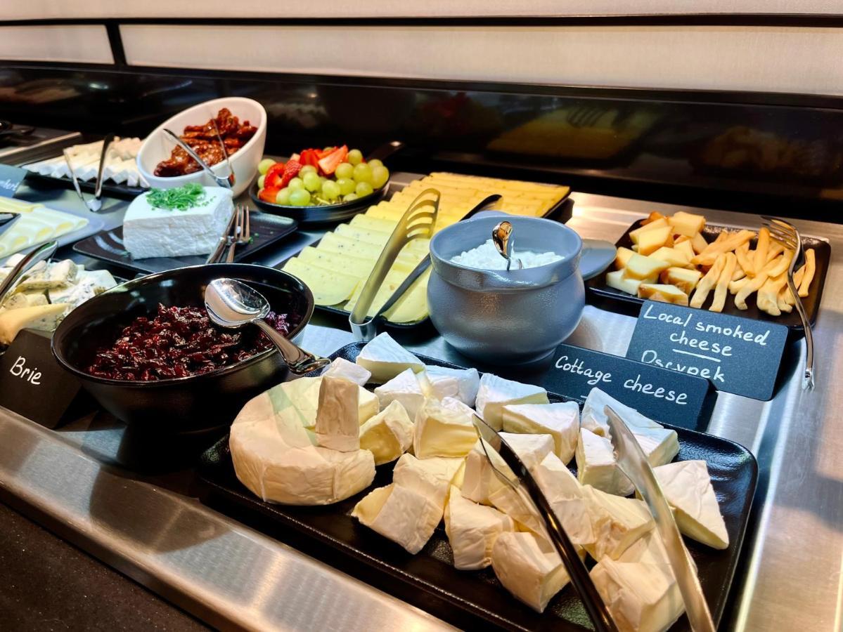 Royal Tulip Warsaw Centre Aparthotel Exterior foto The photo shows a variety of cheeses and accompaniments arranged on a buffet display. There are several types of cheese, including Brie and a soft cheese that appears to be cottage cheese. There's also a bowl of dark-colored cheese, likely a spread. 
