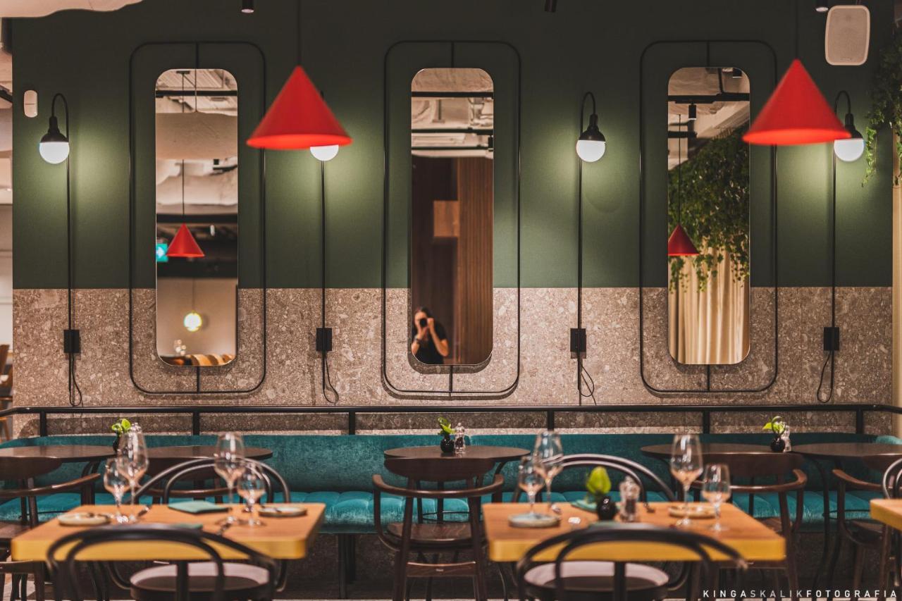 Royal Tulip Warsaw Centre Aparthotel Exterior foto The photo depicts a modern restaurant interior characterized by a stylish design. The walls are painted in dark green, featuring several mirrors set in unique frames. Bright red pendant lights hang from the ceiling, adding a pop of color to the space