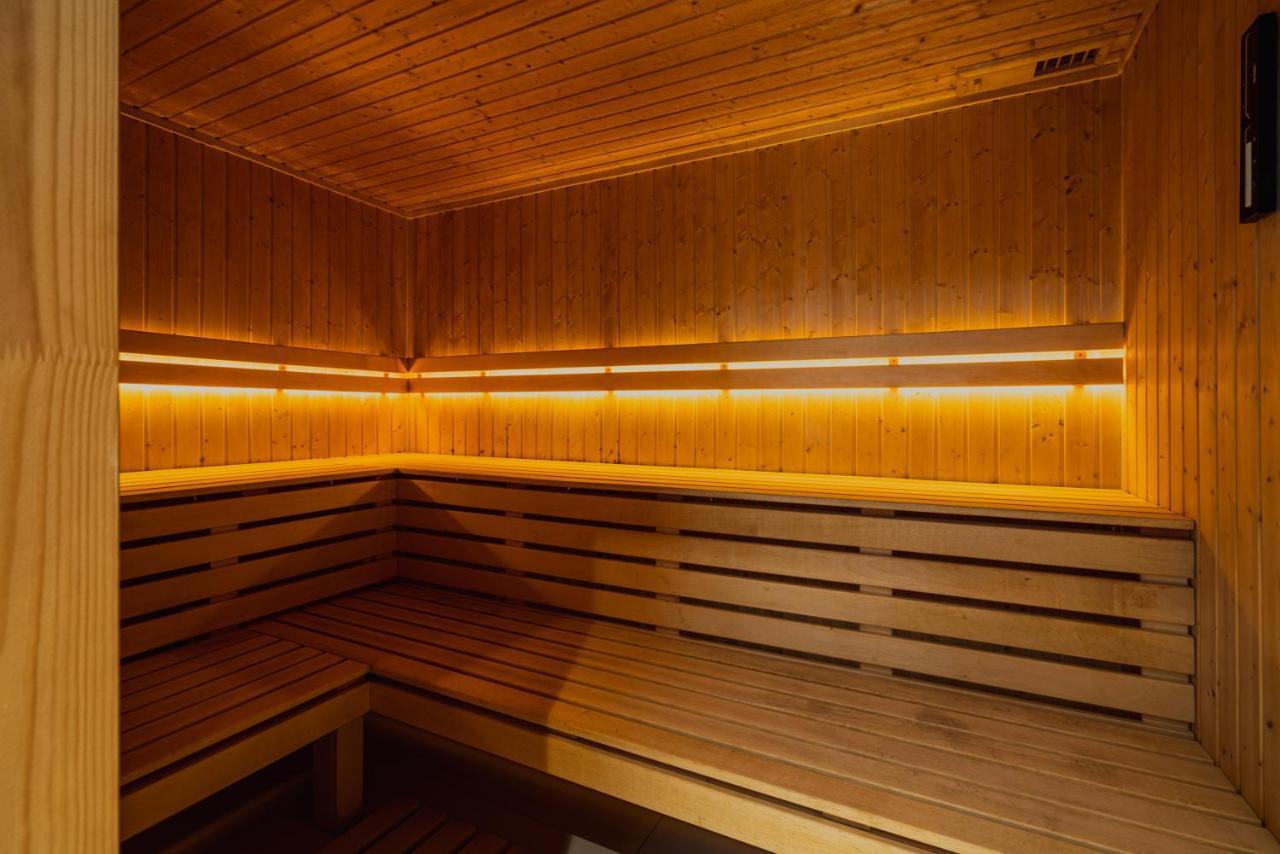 Royal Tulip Warsaw Centre Aparthotel Exterior foto The photo shows the interior of a sauna. It features wooden walls and benches, creating a warm and cozy environment. The lighting is dim but highlights the wood's natural grain, contributing to a relaxing atmosphere. The design includes benches that 
