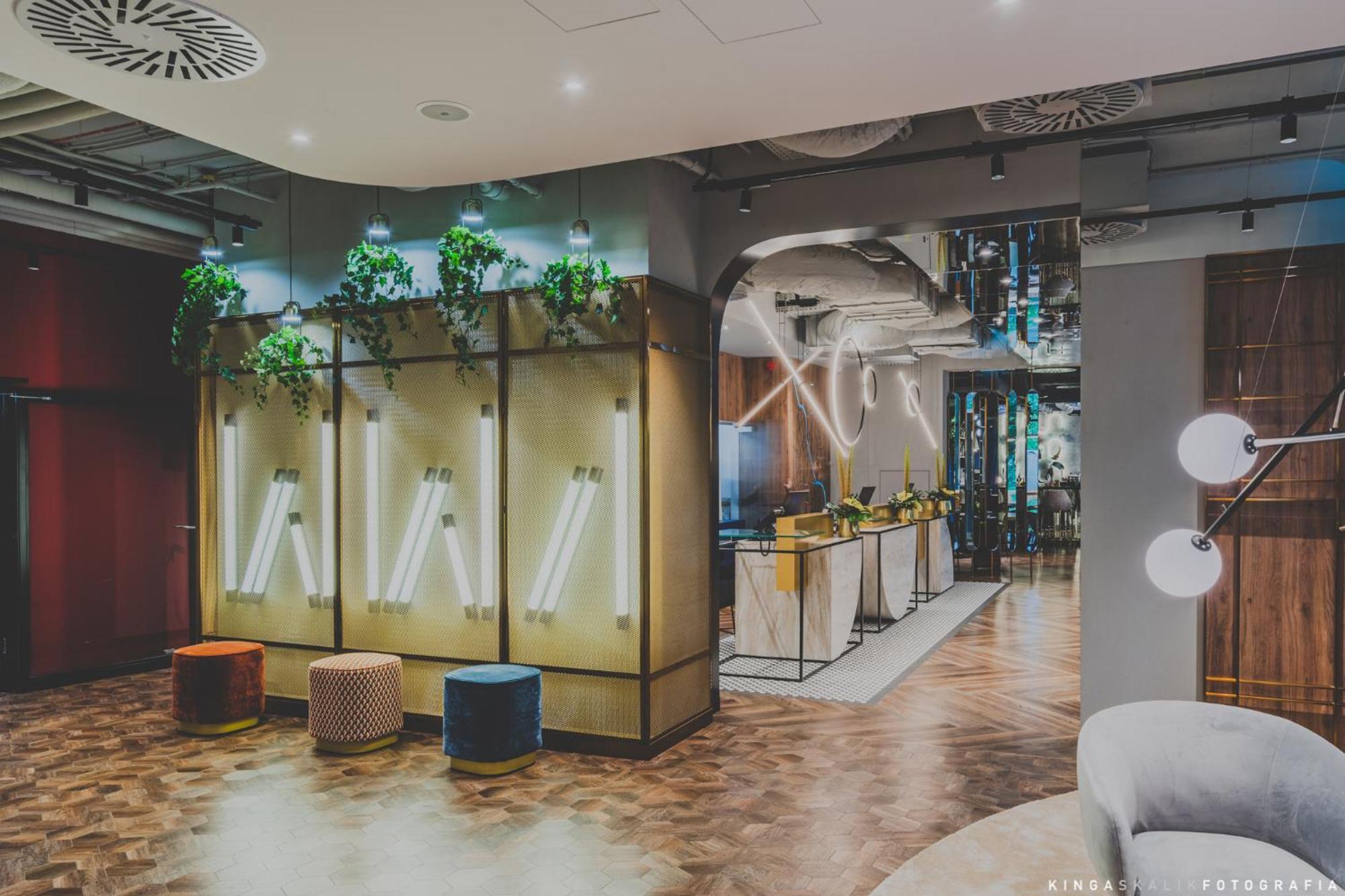 Royal Tulip Warsaw Centre Aparthotel Exterior foto The photo shows a modern interior space, likely a lobby or lounge area. The design features a combination of stylish furniture and decorative elements. There are illuminated wall panels integrated with greenery, creating a fresh aesthetic. In the bac