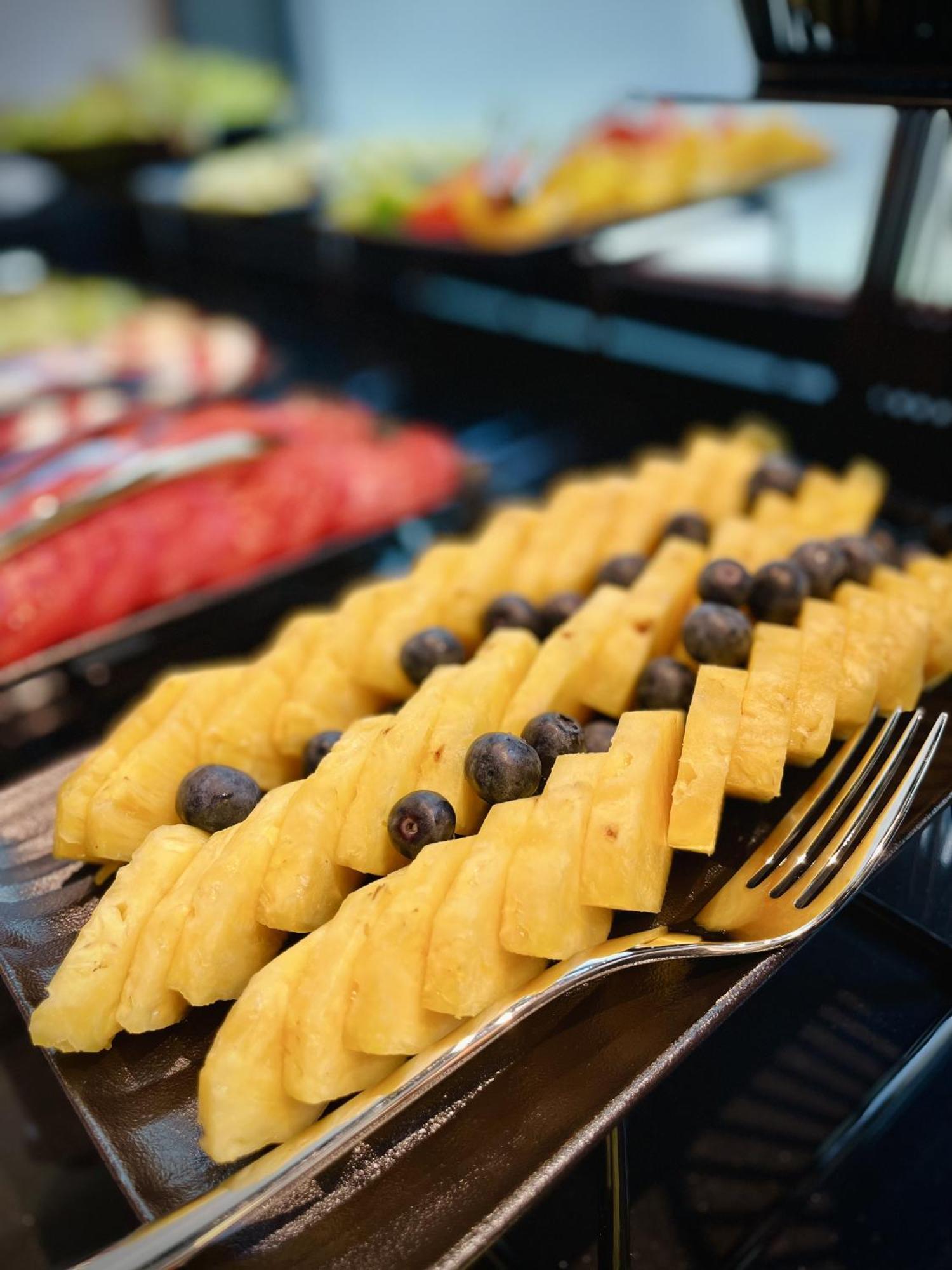 Royal Tulip Warsaw Centre Aparthotel Exterior foto The photo shows a colorful fruit display featuring neatly arranged slices of yellow pineapple, interspersed with dark blueberries. The pineapple slices are cut into a checkerboard pattern, creating an appealing presentation. In the background, other 