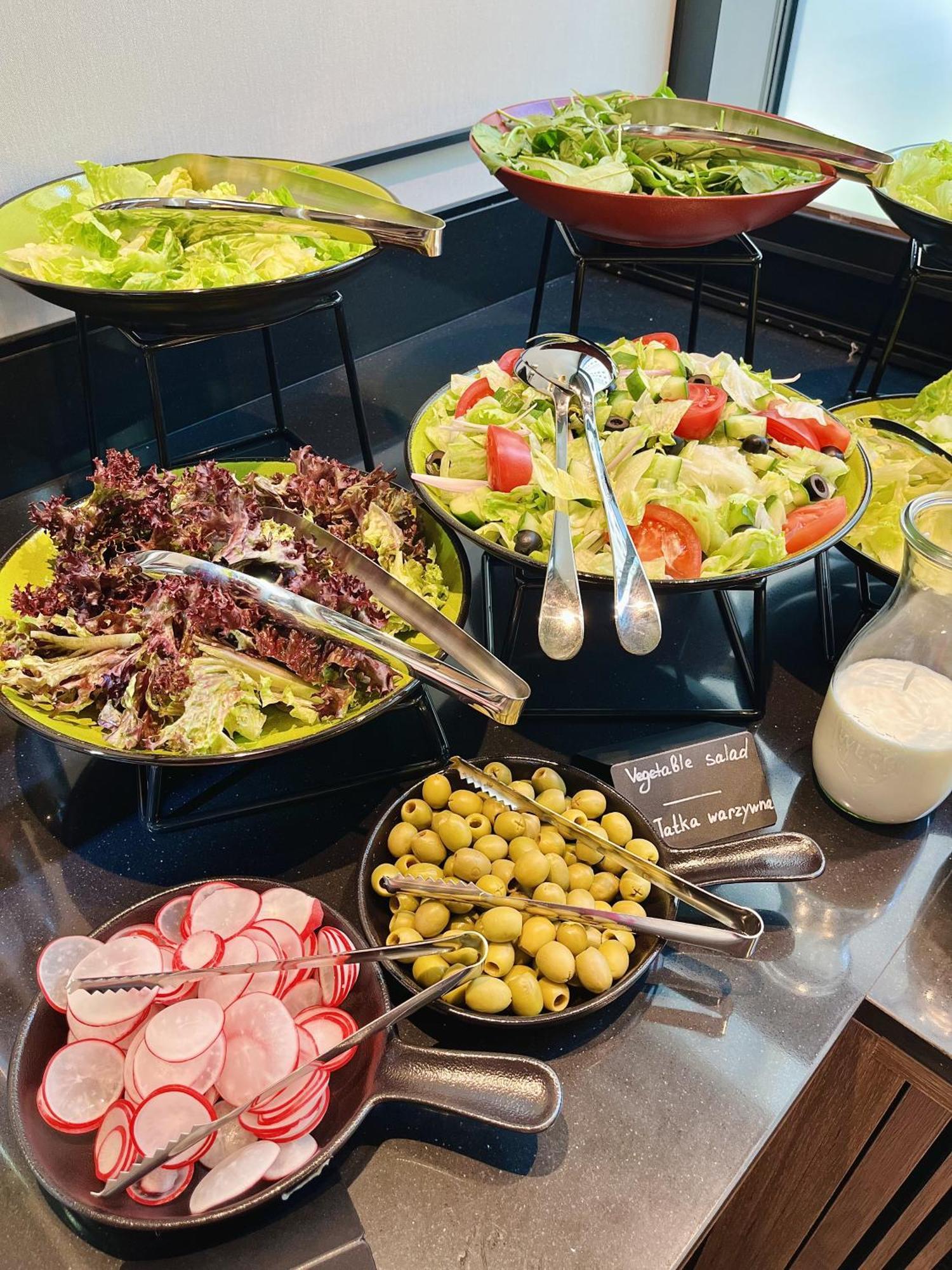 Royal Tulip Warsaw Centre Aparthotel Exterior foto The photo shows a variety of salad options arranged on a table. 

1. **Salads**: There are two larger bowls—one with mixed greens, including red leaf lettuce, and another with a colorful salad that includes chopped tomatoes, cucumbers, and olives.
2.