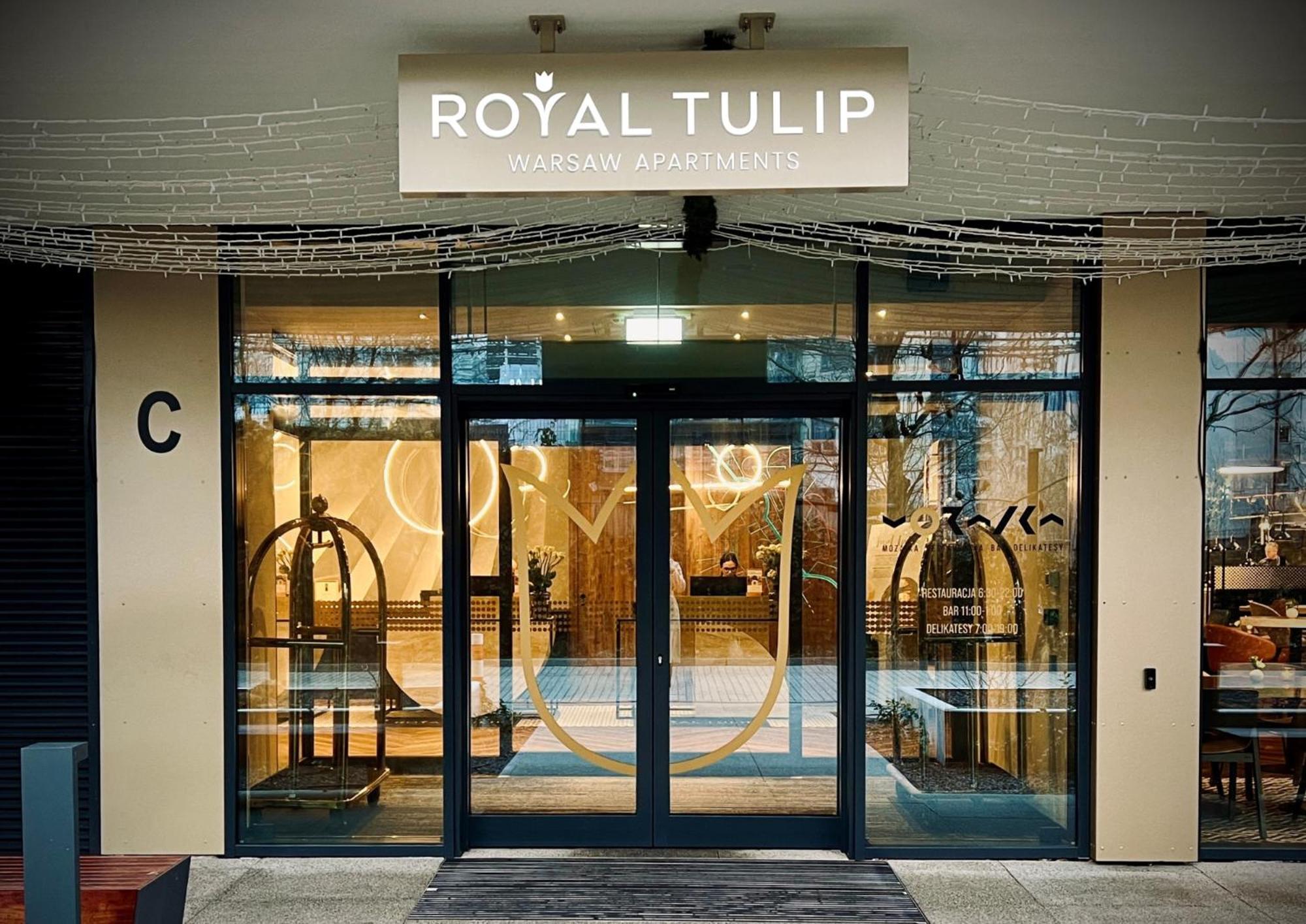 Royal Tulip Warsaw Centre Aparthotel Exterior foto The photo shows the entrance to a hotel named "Royal Tulip." The facade features large glass doors that allow a view into the lobby area. There are decorative elements, including what appears to be luggage carts near the entrance. Above the doors is 