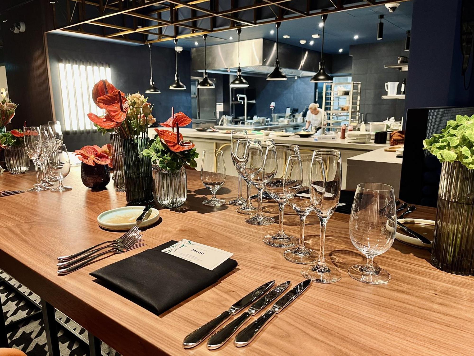 Royal Tulip Warsaw Centre Aparthotel Exterior foto The photo shows a beautifully arranged dining area in a restaurant. There is a long wooden table set with elegant glassware, including wine glasses and water glasses. Each place setting includes polished silverware and a folded napkin with a card on 